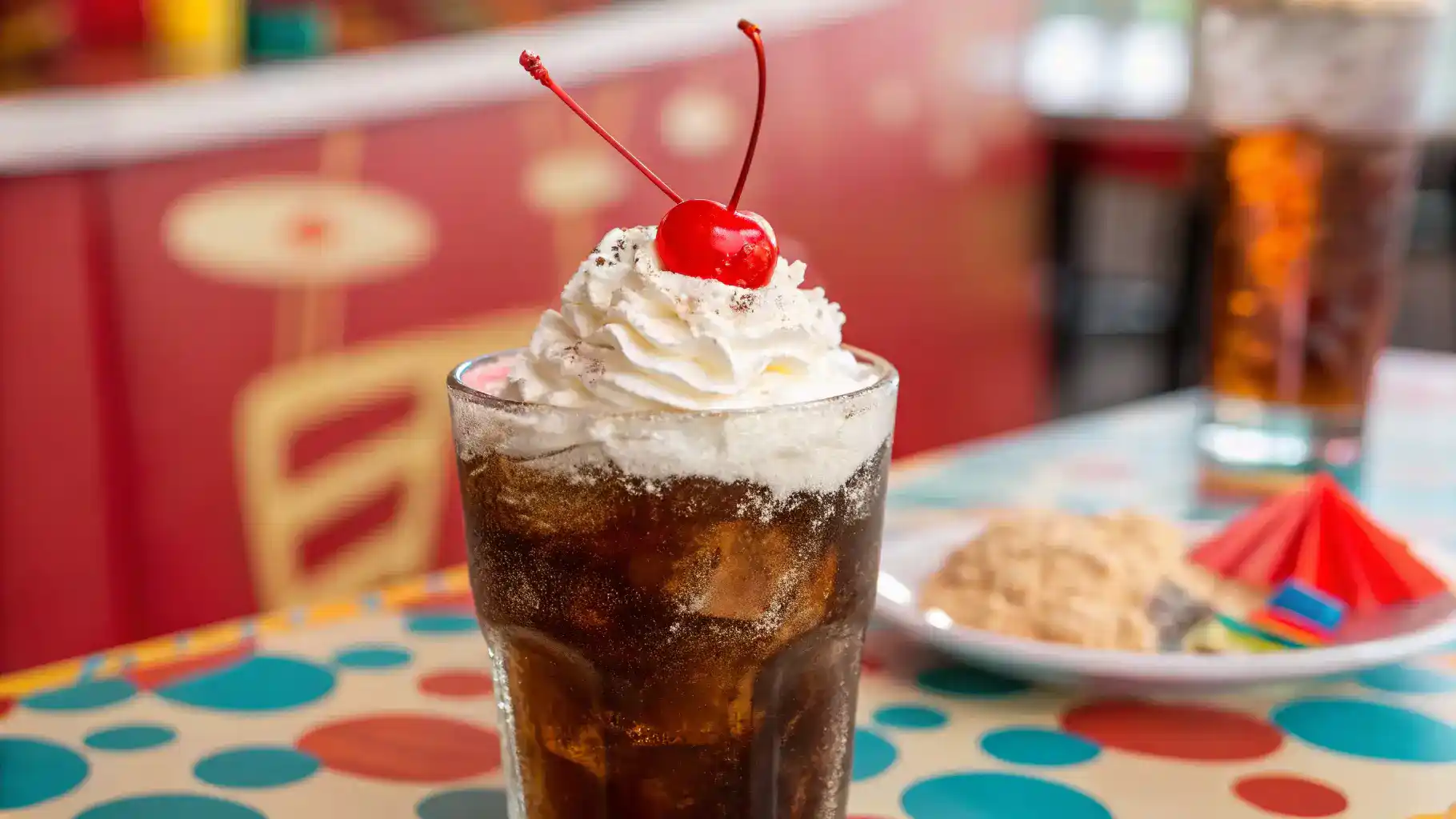 A refreshing glass of dirty soda topped with whipped cream and a cherry.